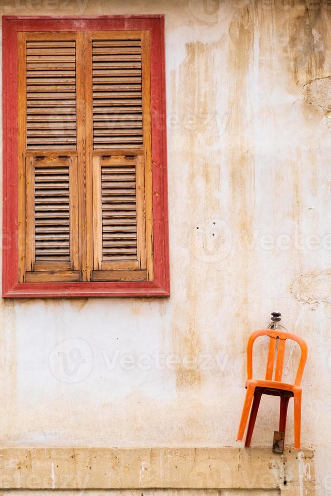 orange stol som hänger på väggen och det vackra träfönstret i ett traditionellt hus i den gamla staden Nicosia, Cypern foto
