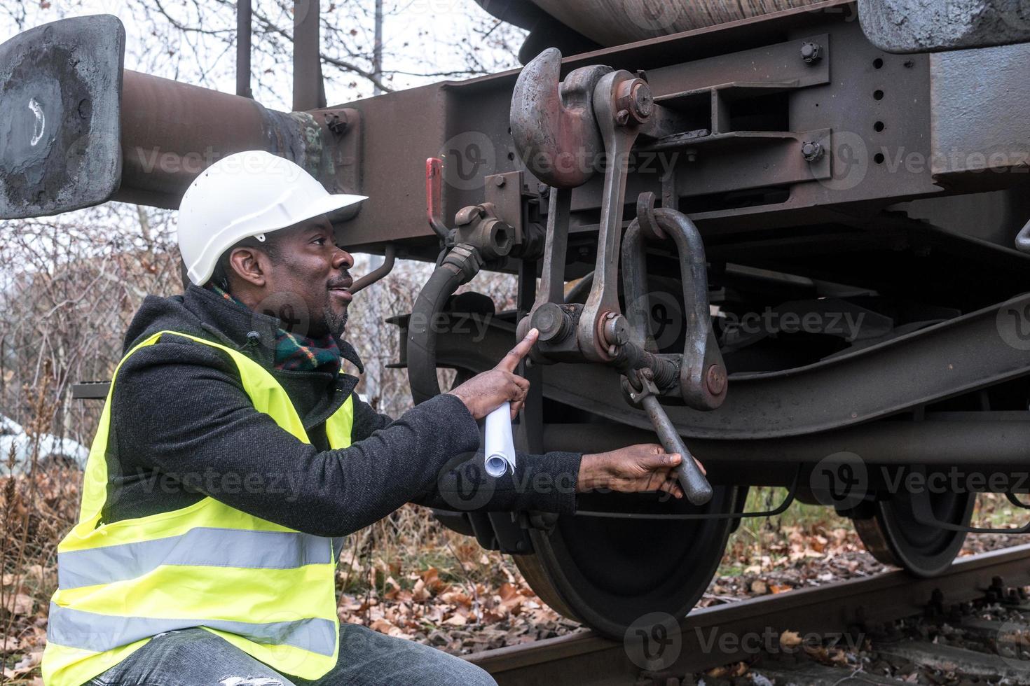 afroamerikansk mekaniker som bär säkerhetsutrustning som kontrollerar och inspekterar redskapståg foto