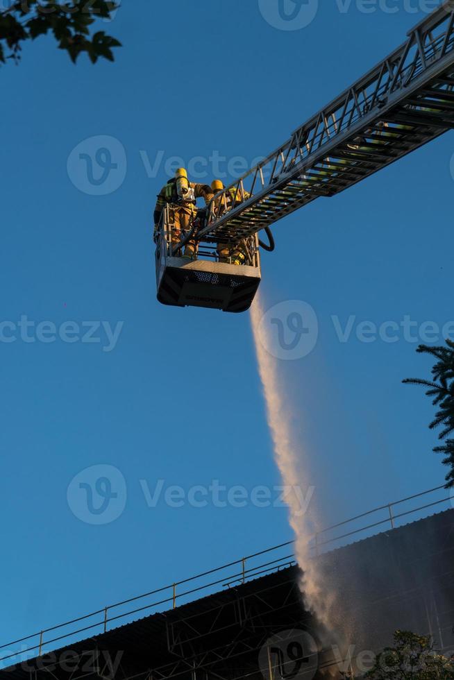 brandmän klättrar stege mot byggnad foto