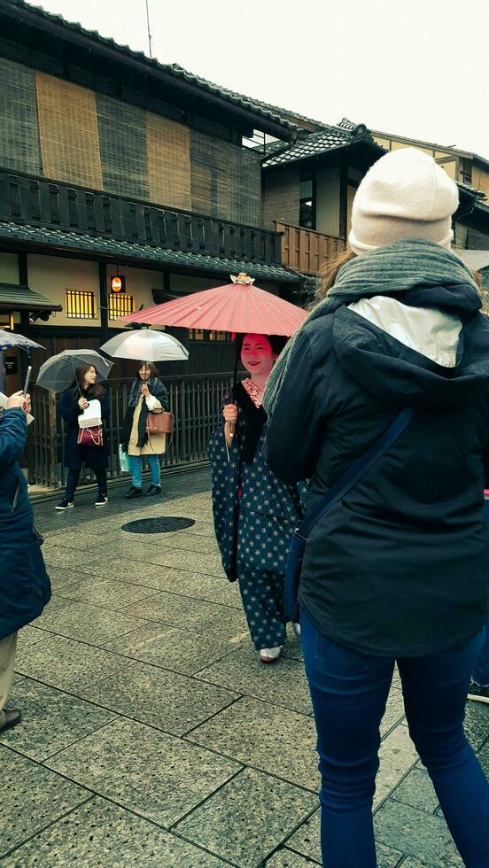 Kyoto, japan på april 8, 2019. människor är gående medan använder sig av paraplyer eftersom den är regnar. foto