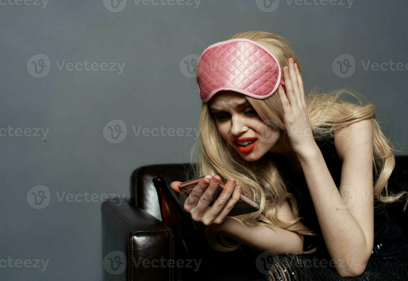 full blond kvinna med mobil telefon smink och rosa sömn mask foto