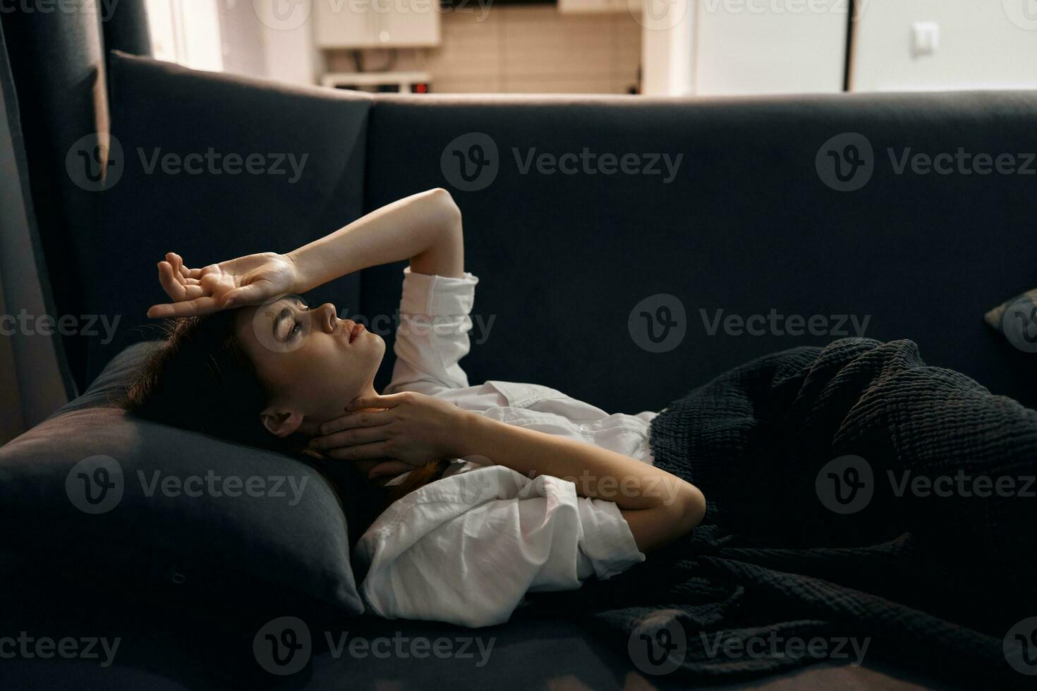 kvinna lögner på de soffa och innehar henne hand på henne huvud resten levande rum foto