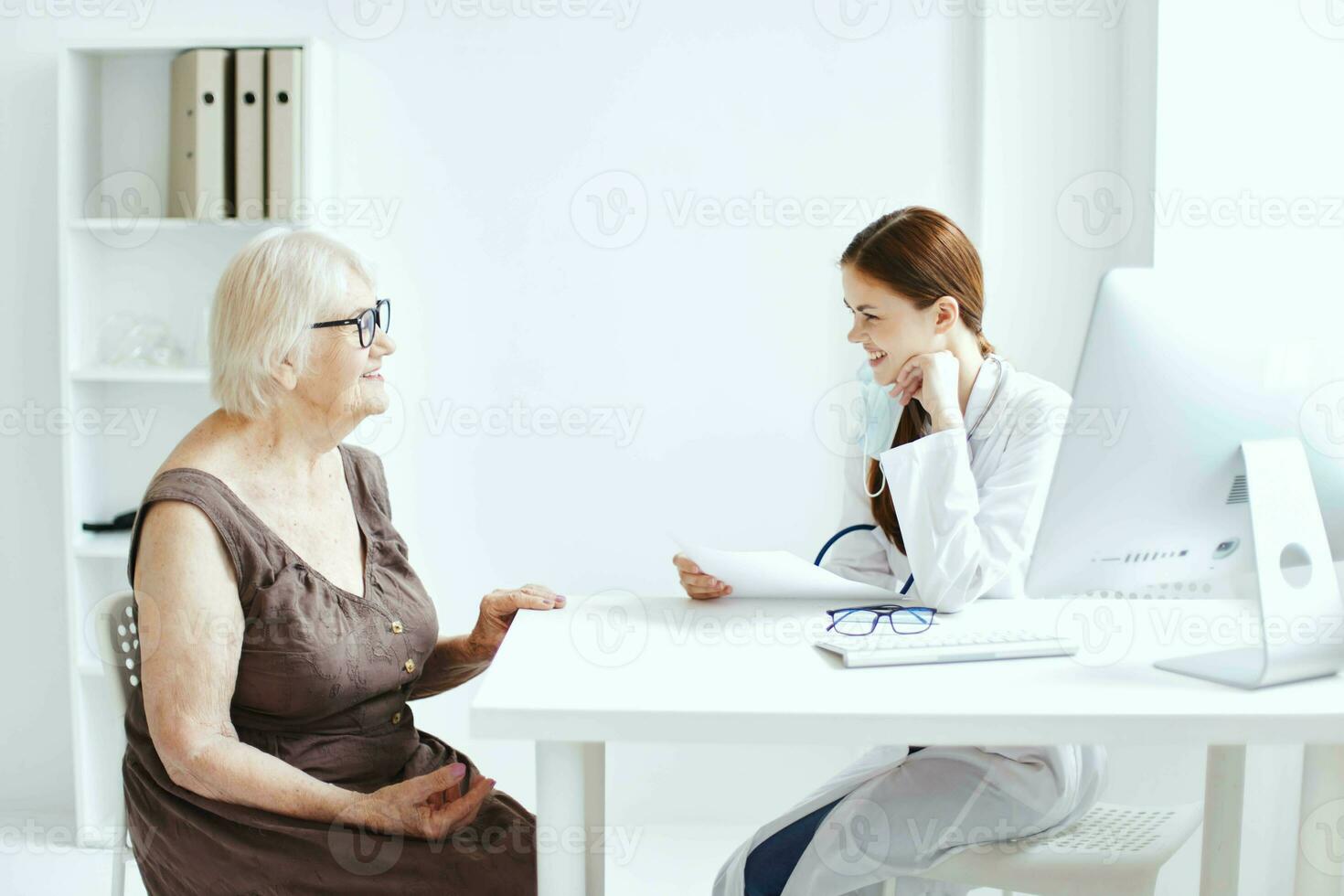 äldre kvinna bär en medicinsk mask på undersökning förbi en sjuksköterska stetoskop foto