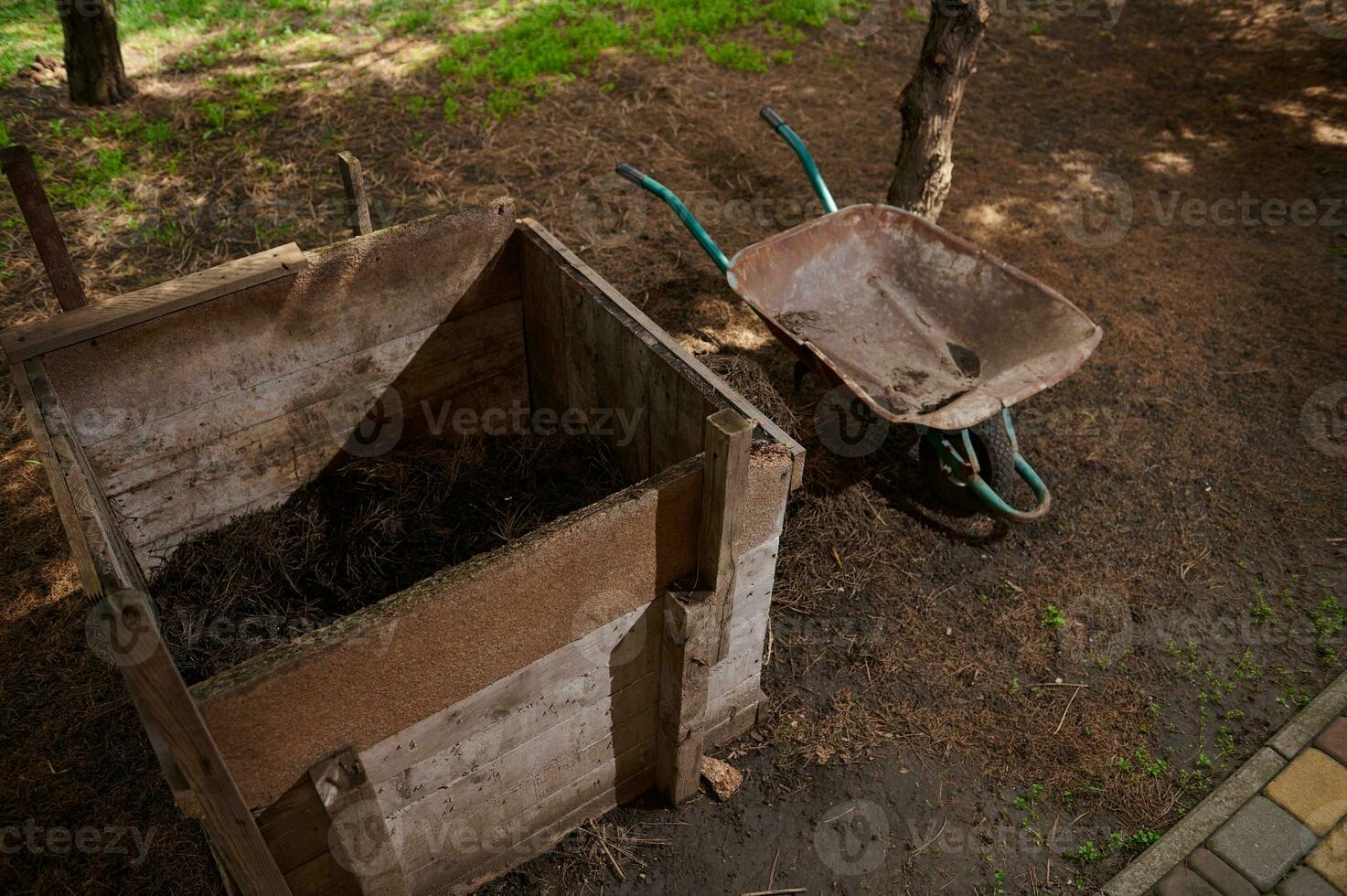 fortfarande liv med en skottkärra stående nära en kompost grop i en trädgård komplott. lantbruk. eco jordbruk. trädgårdsarbete. foto