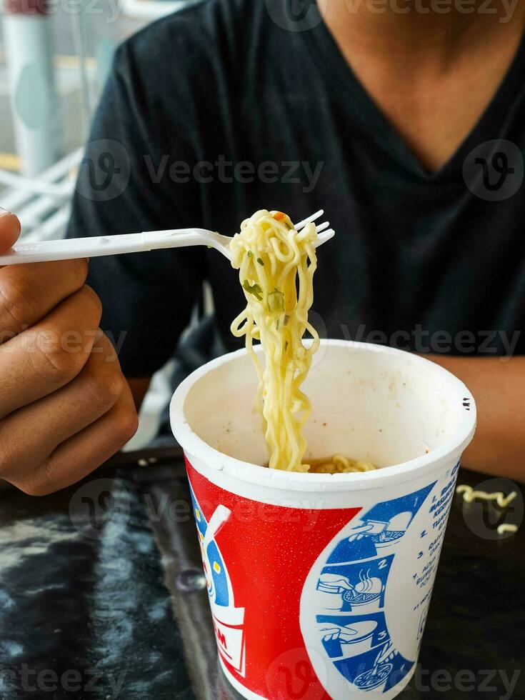 omedelbar spaghetti, nudel soppa i en kopp, Pojkar hand matning redo till äta spaghetti foto