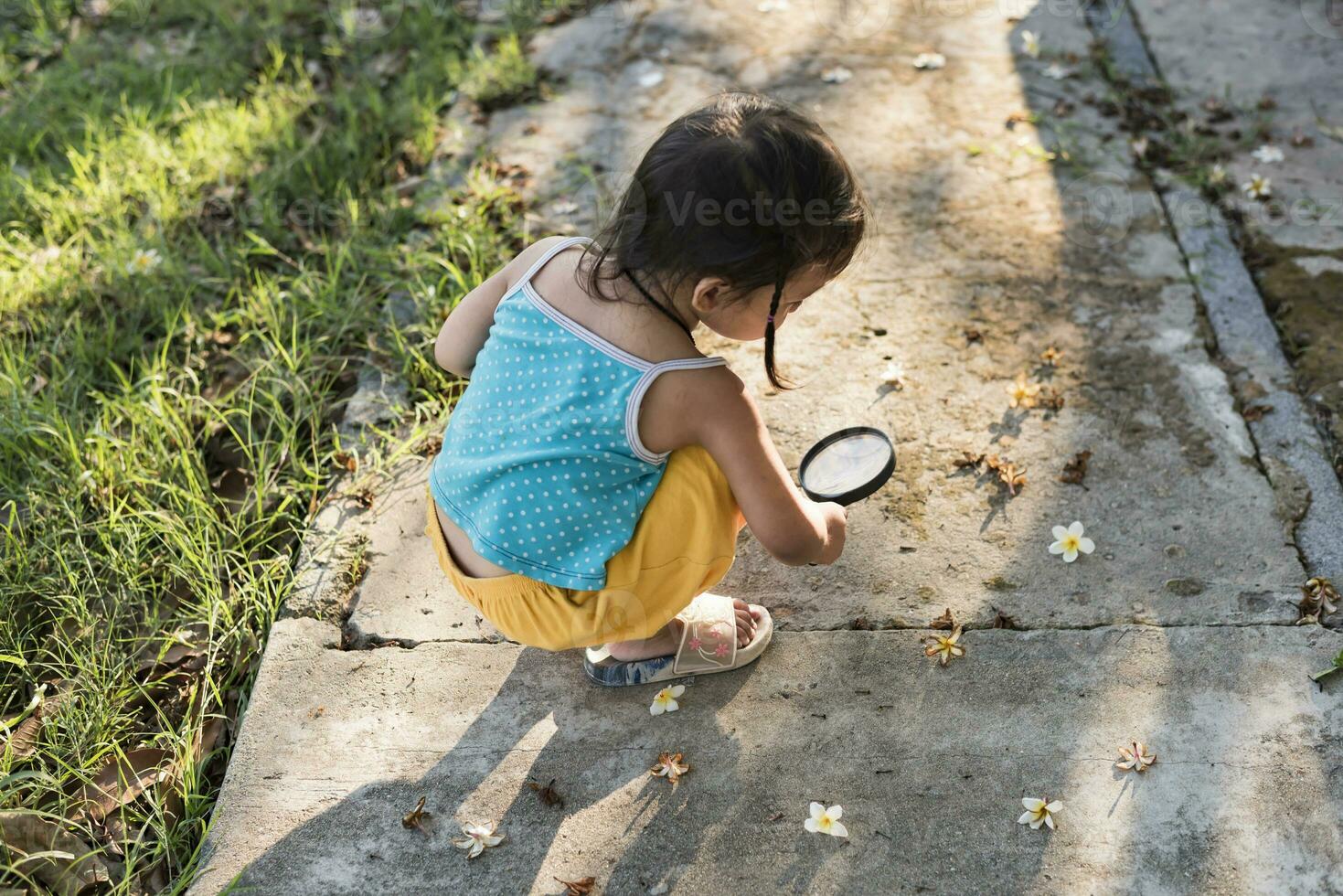 bild av söt unge med förstorande glas utforska de natur utomhus. förtjusande liten flicka spelar i de skog med förstorande glas. nyfiken barn ser genom förstoringsglas på en solig dag i parkera foto