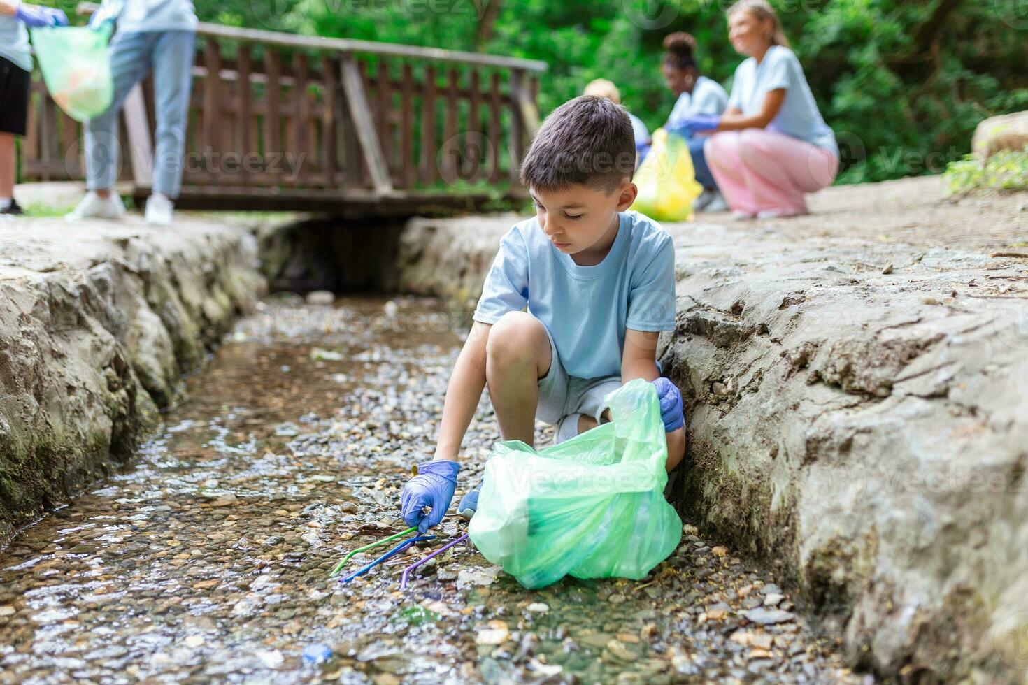 unge pojke handplockning sammankomst upp sopor plast strån sopor från de flod på de parkera. värld miljö dag.miljö begrepp. foto