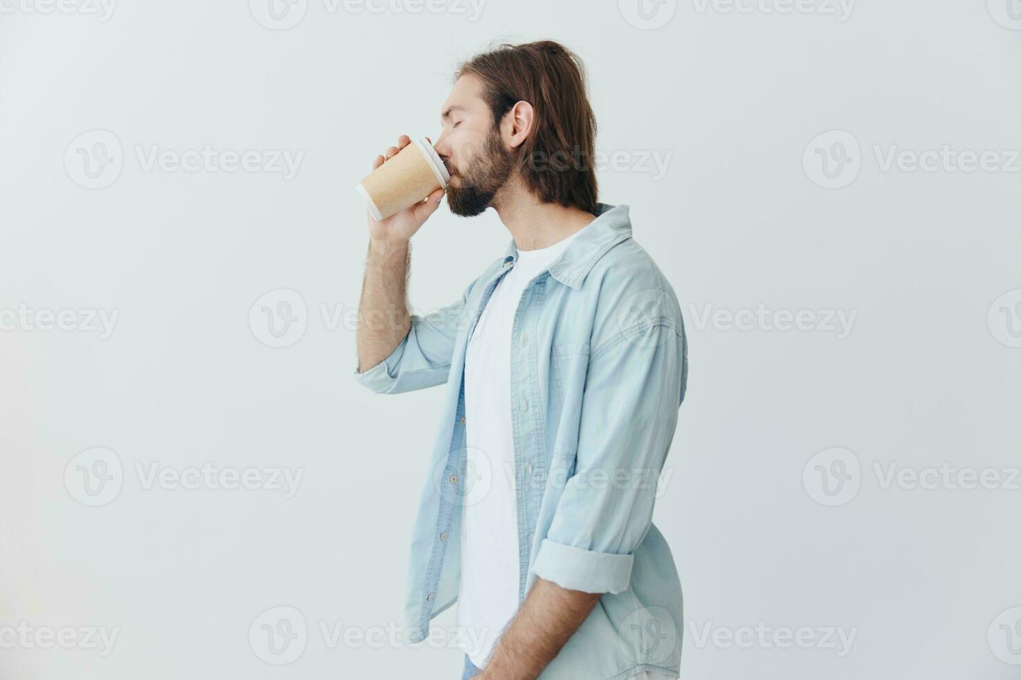frilans tusenåriga man med skägg dricka kaffe från en krabba kopp i eleganta hipster kläder på en vit bakgrund foto