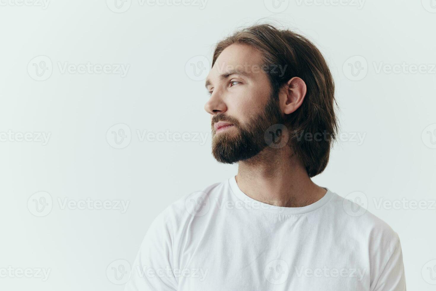 porträtt av en ledsen man med en svart tjock skägg och lång hår i en vit t-shirt på en vit isolerat bakgrund foto