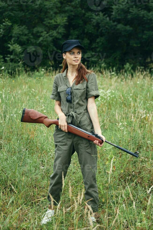 kvinna på utomhus- innehar en vapen i en grön overall färsk luft vapen foto