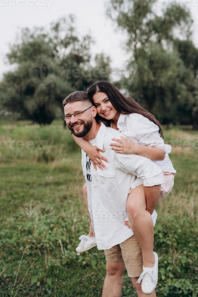 ungt par i kärlek en kille med skägg och en tjej med mörkt hår i ljusa kläder foto