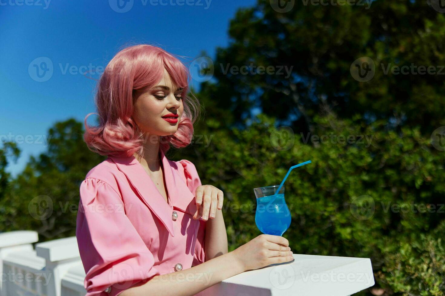 porträtt av skön kvinna i rosa klänning utomhus med cocktail avslappning begrepp foto