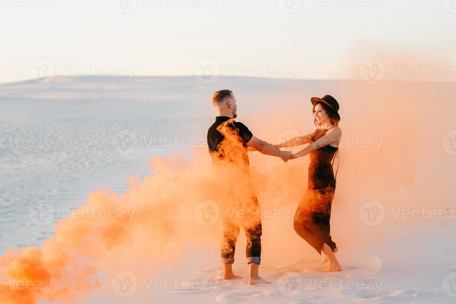 kille och en flicka i svarta kläder kramar och springer på den vita sanden foto