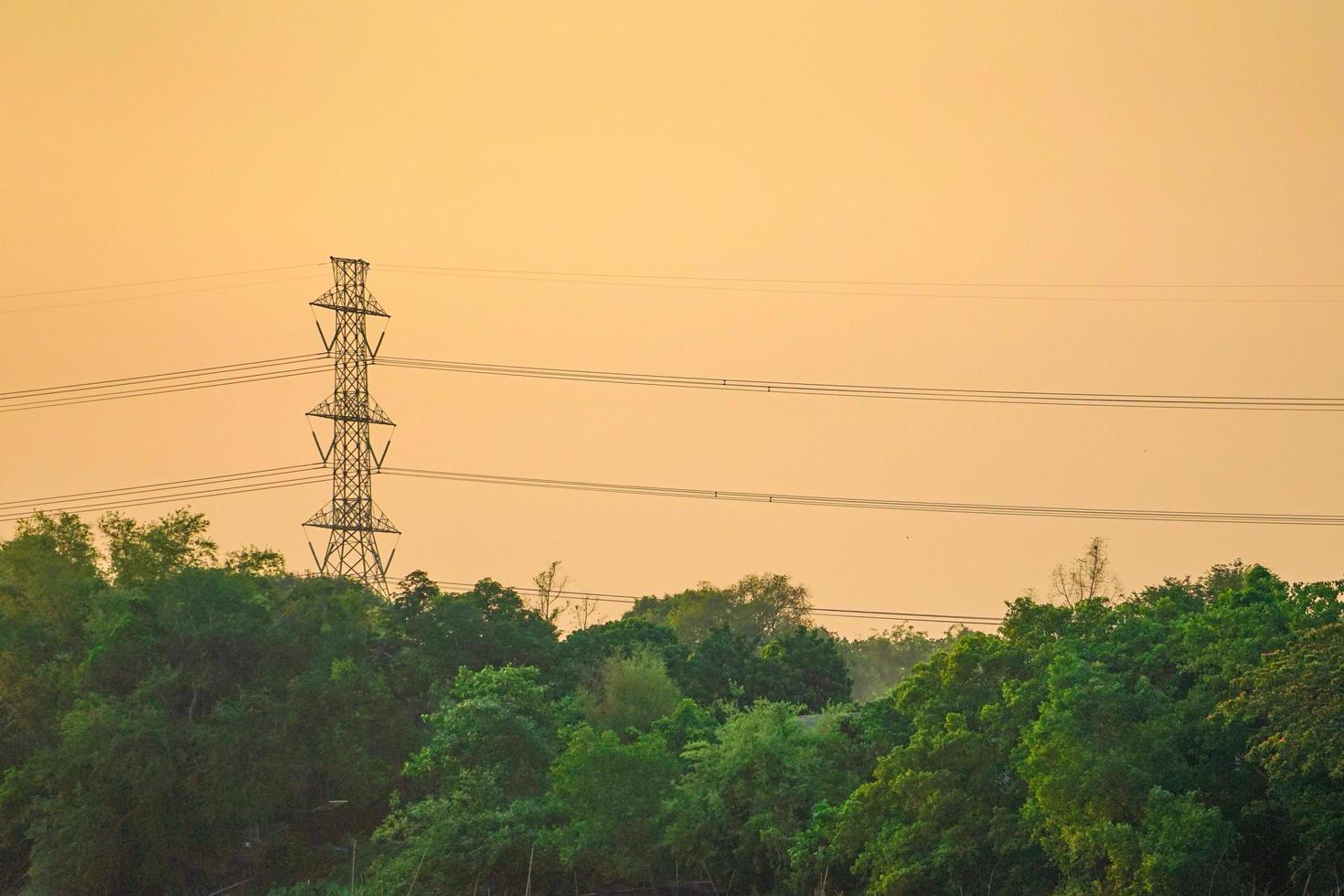 högspänning el torn och kabel med orange himmel solnedgång bakgrund, landskap av tropisk skog foto