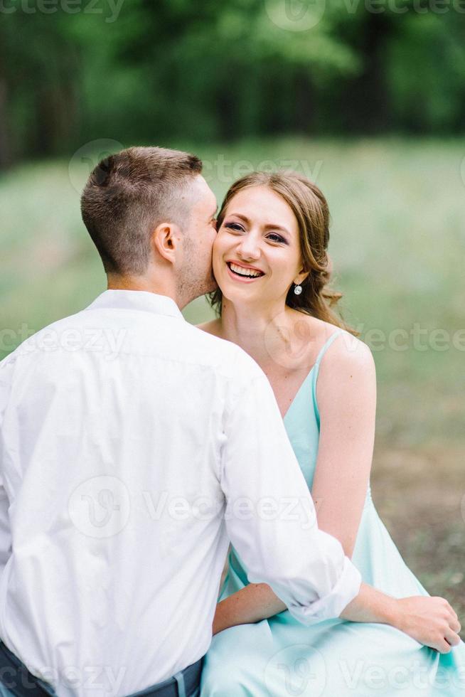 glad kille i en vit skjorta och en flicka i en turkos klänning går i skogsparken foto