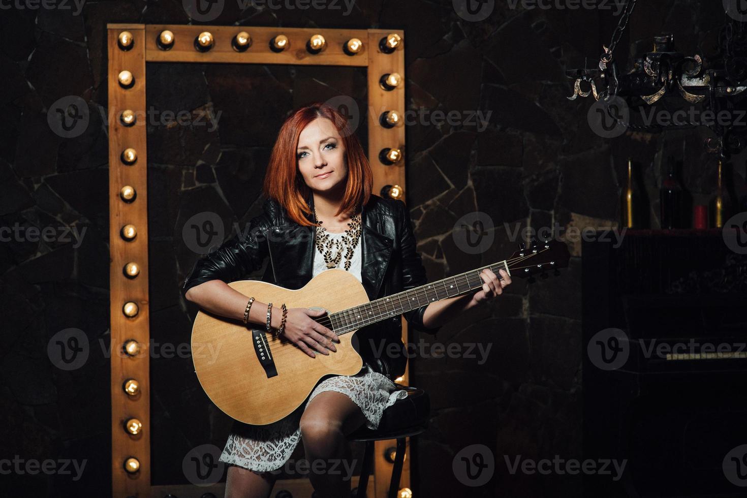 ung flicka med rött hår med en akustisk gitarr foto