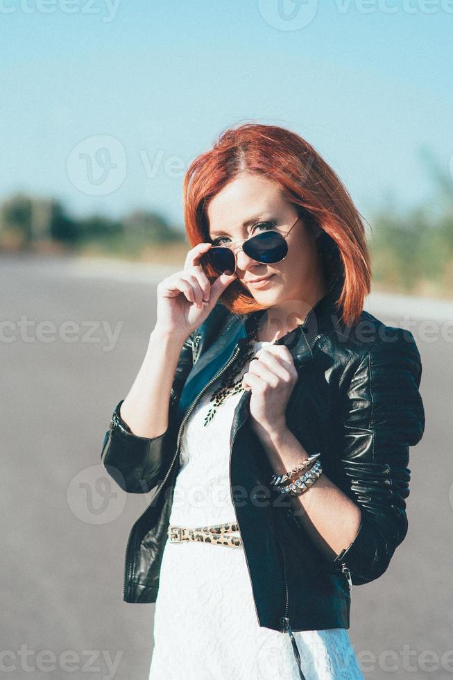 rödhårig flicka i en svart jacka och blå glasögon foto