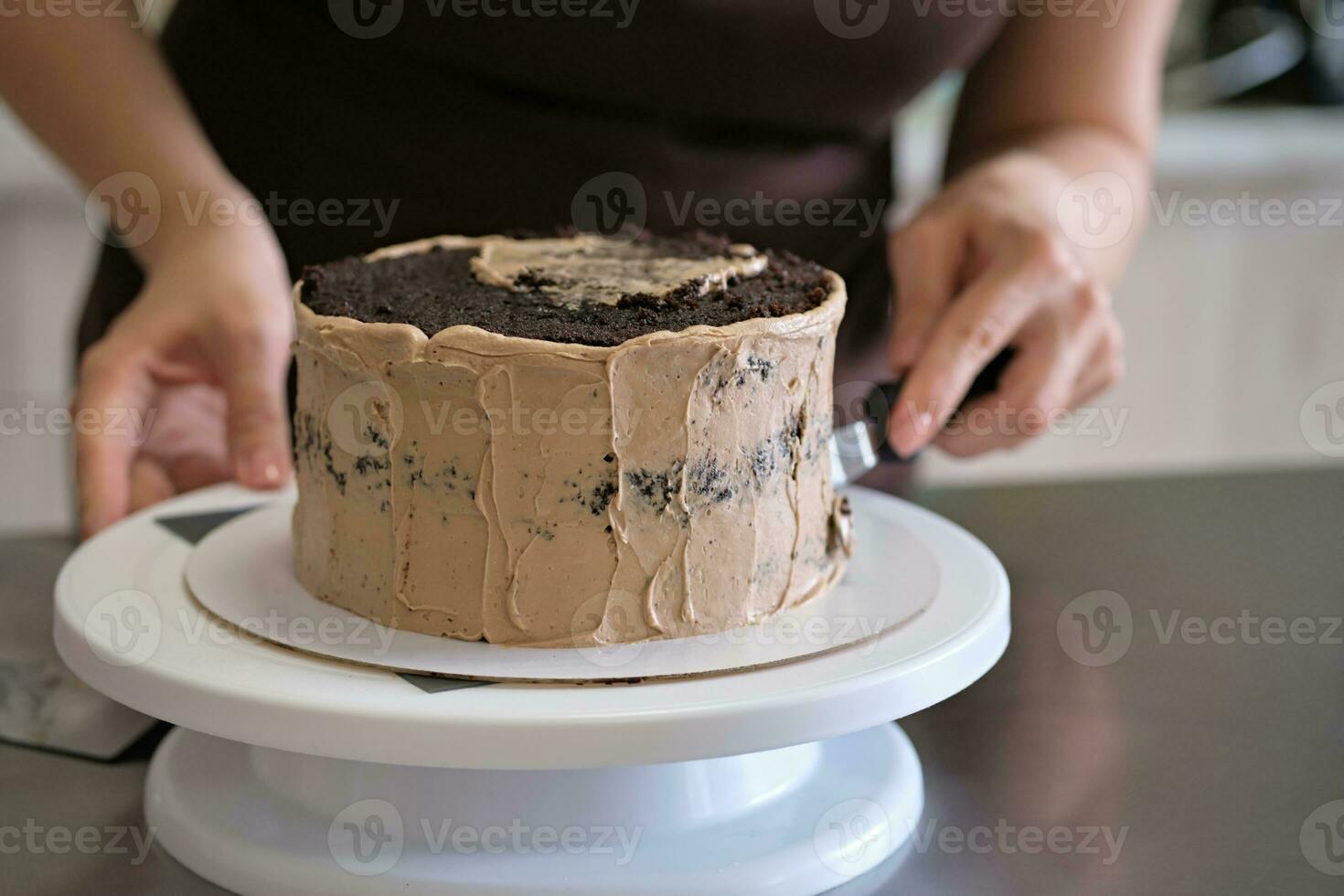 kvinna bakverk kock framställning choklad kaka med choklad grädde, närbild. kaka framställning bearbeta, selektiv fokus foto