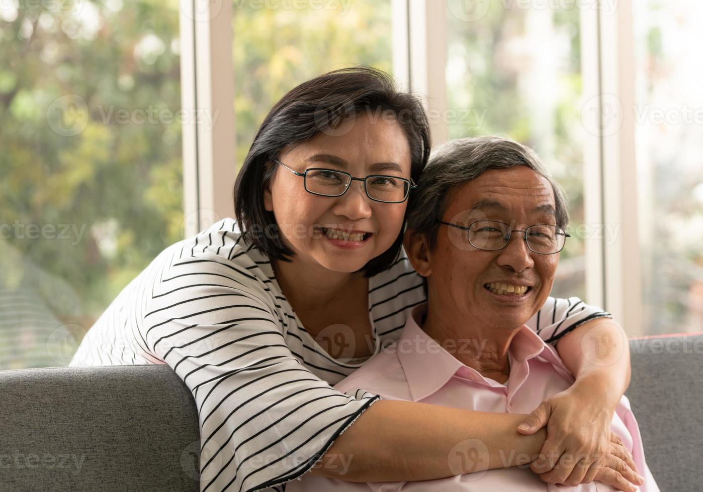 senior asiatisk man och kvinna kopplar av på semester i den naturliga vardagsrumsbakgrunden med modern teknik foto