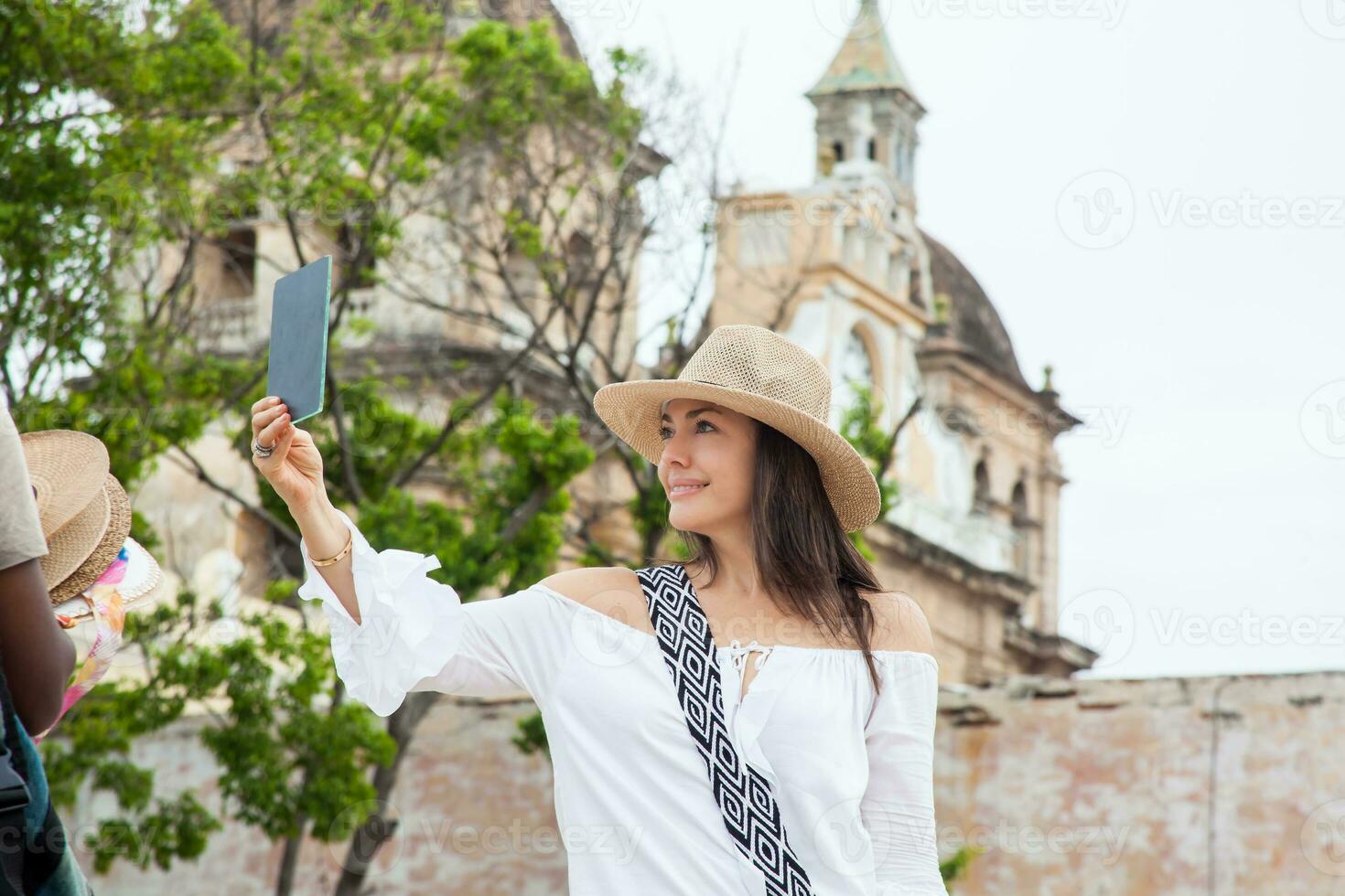 skön ung kvinna påfrestande på hattar till köpa ett från ett gata Säljare i cartagena de Indien walled stad foto