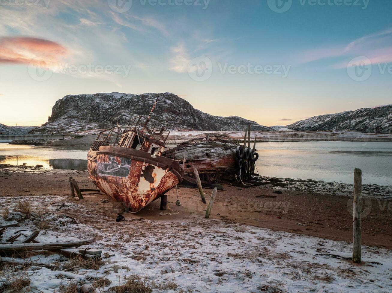 ett gammal rostig fiske båt övergiven förbi en storm på de Strand. kyrkogård av fartyg, gammal fiske by på de Strand av de barents hav, de kola halvö, teriberka foto