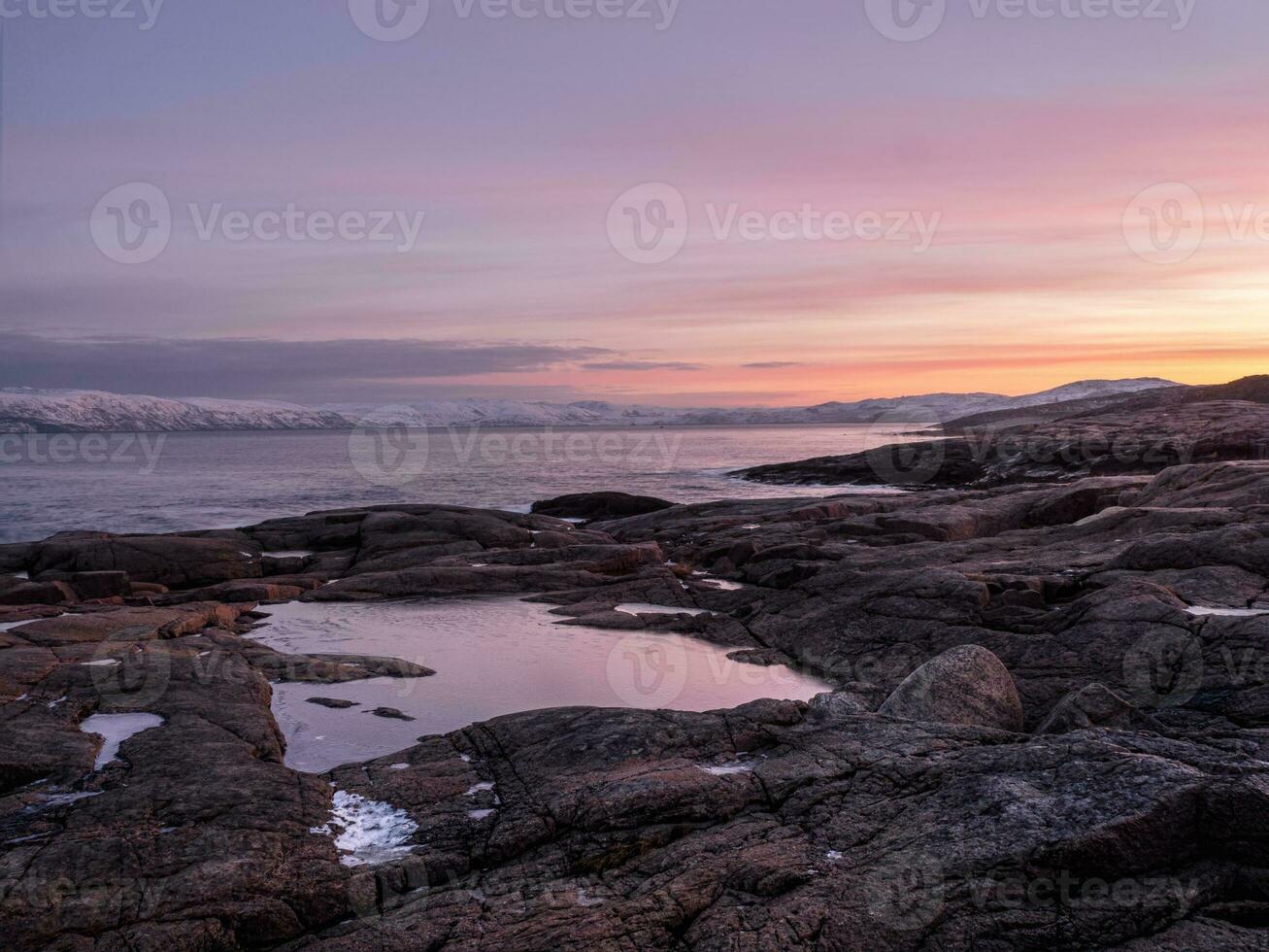 underbar berg landskap med en cape på de Strand av de barents hav. Fantastisk soluppgång landskap med polär vit snöig räckvidd av berg. foto