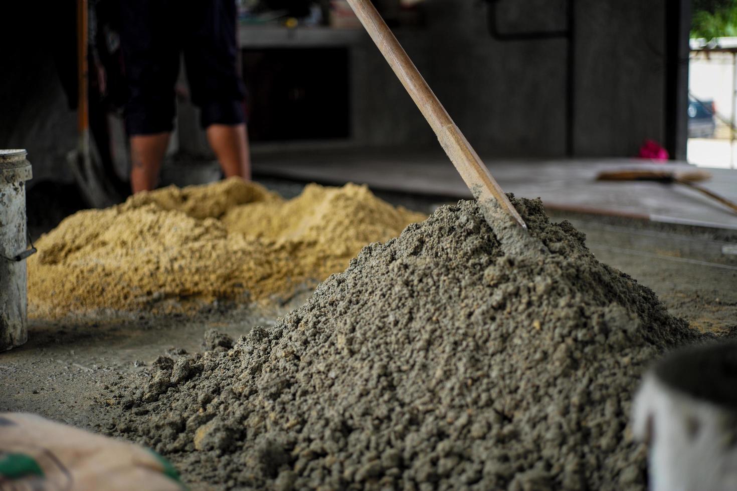 selektivt fokus på ytan av blandad cementhög med suddig bakgrund av sand på byggarbetsplatsen foto