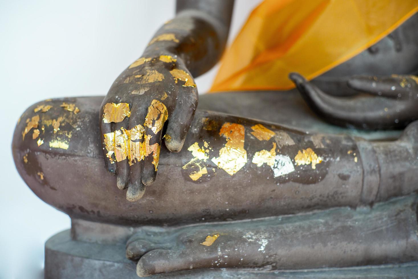 selektiv fokus på närbildhand av Buddhastatyn belagd med det gyllene bladet foto