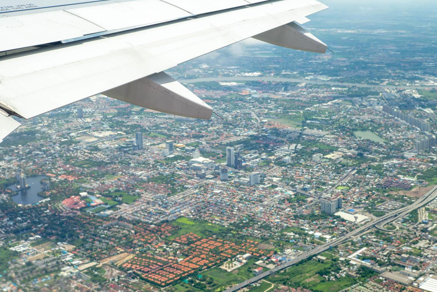 närbild vinge av flygplan medan du flyger i luften med stadsbilden nedan foto