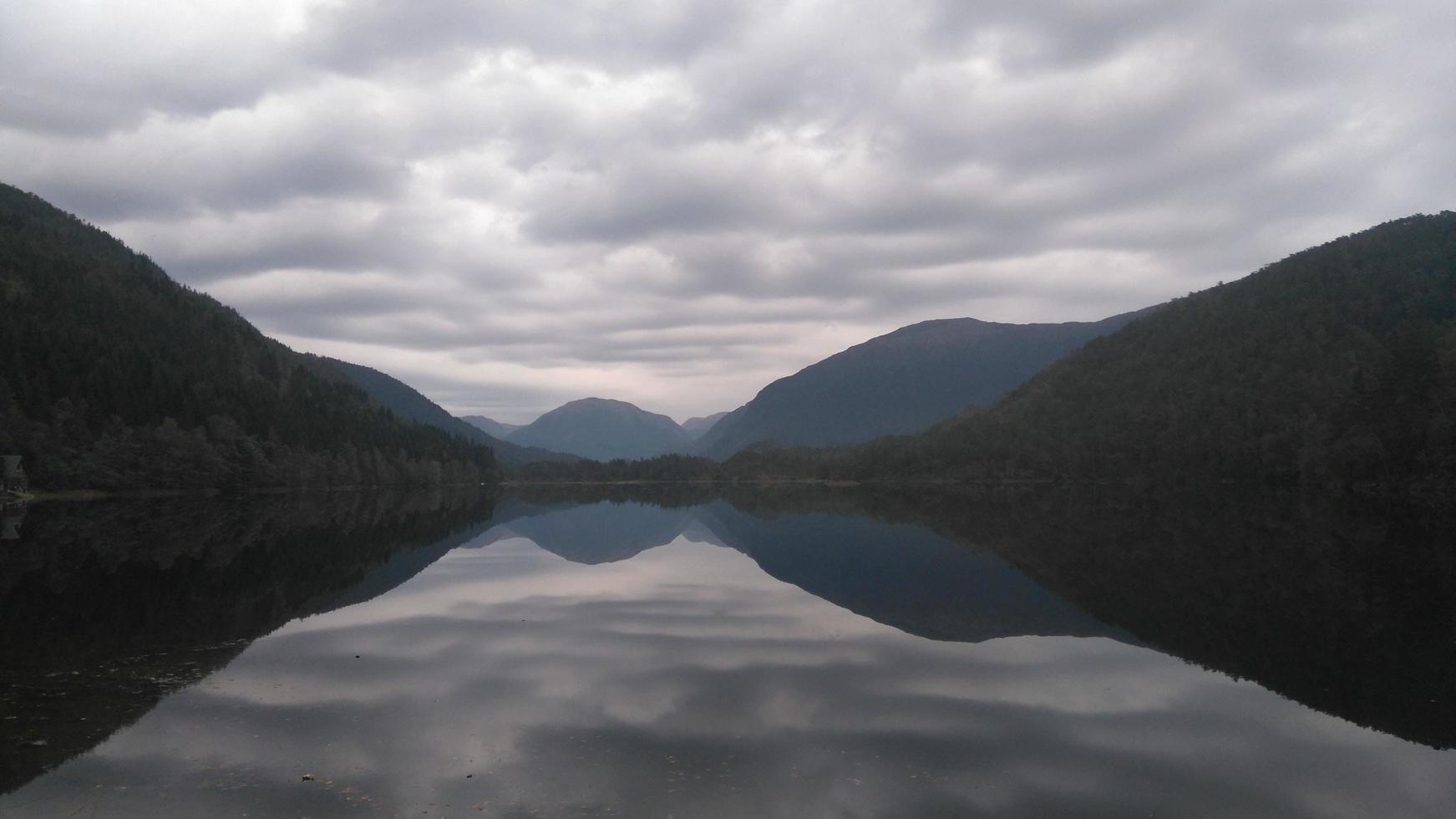 silhuetter och reflektioner av berg i vatten foto