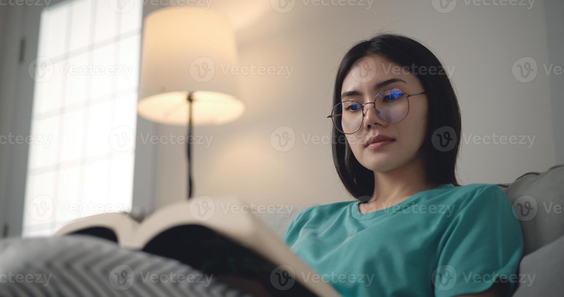 antal fot av Lycklig ung asiatisk kvinna läsning en bok foto