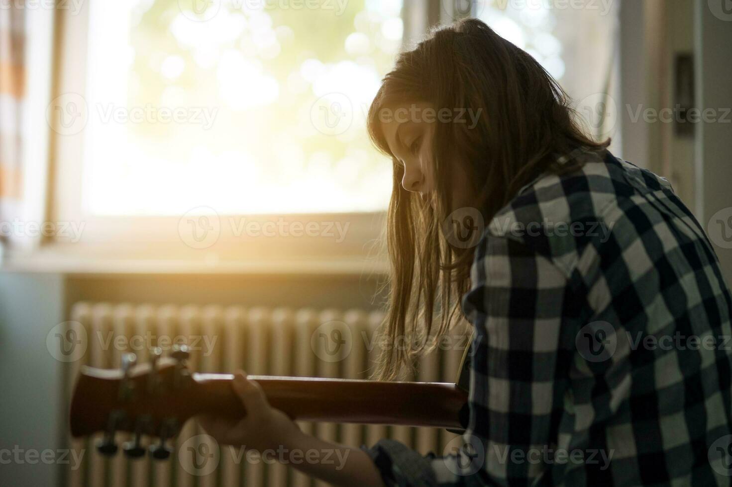 en Tonårs flicka spelar gitarr foto