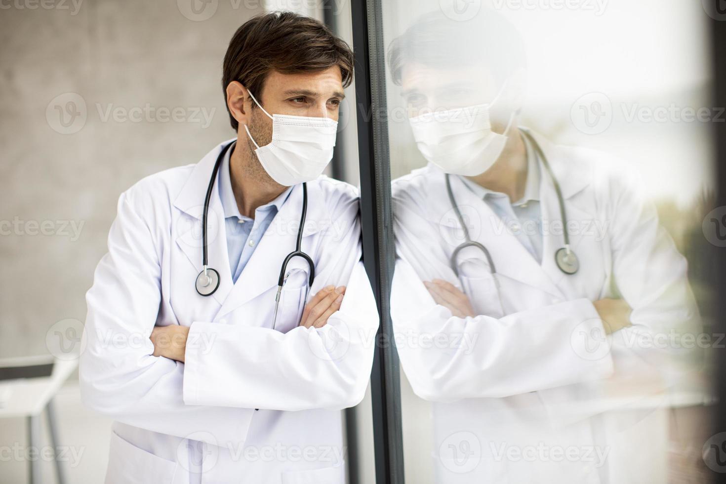 läkare som bär en mask med reflektion i ett fönster foto