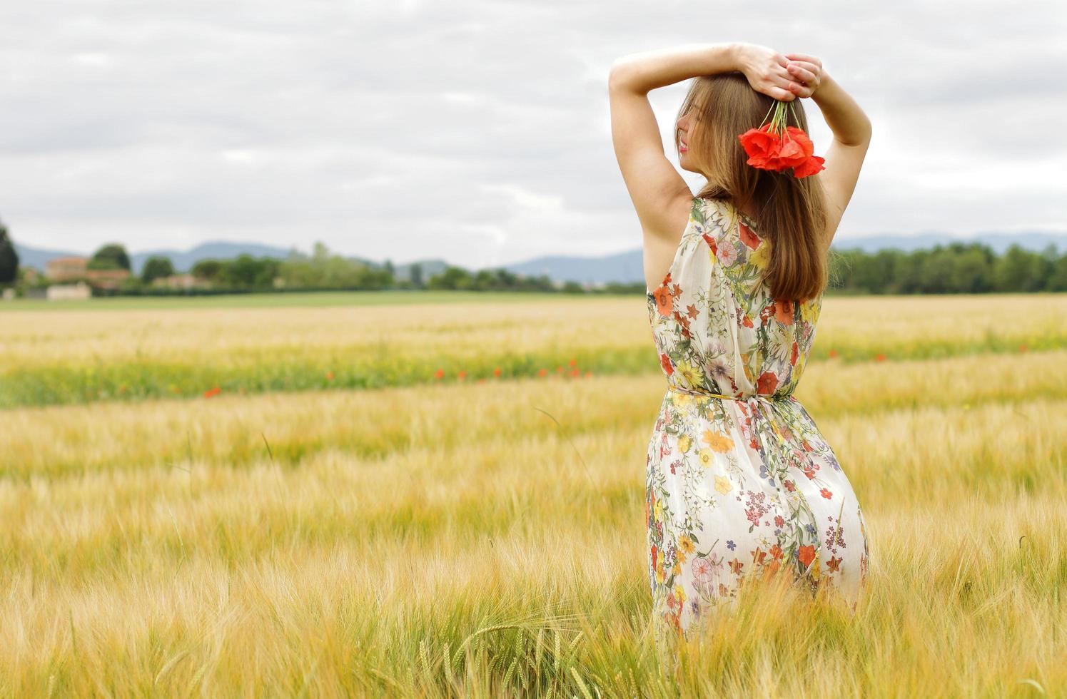 kvinna i en blommig klänning med blommor i ett fält foto