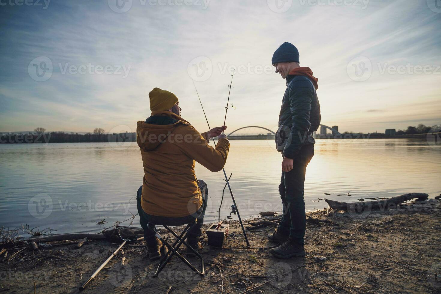 far och son är fiske på solig vinter- dag foto