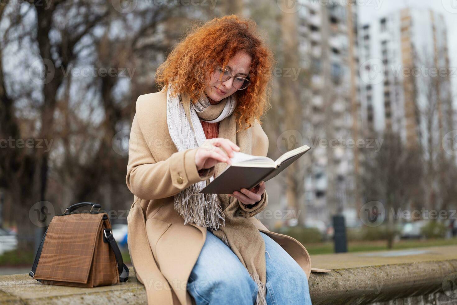 ung kvinna med fräknar och lockigt ingefära hår med anteckningsbok utomhus foto