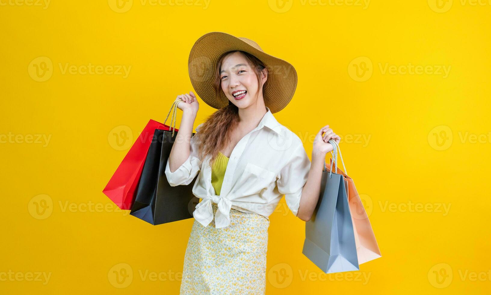 Söt asiatisk kvinna i trendig sommar mode är leende och innehav handla väska i lycka för rabatt försäljning isolerat på gul bakgrund för reklam och befordran händelse foto