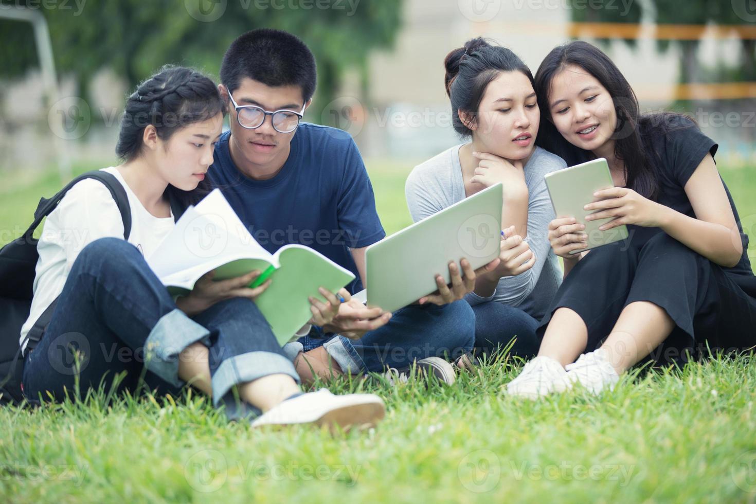asiatiska studenter som studerar på gräsmattan foto