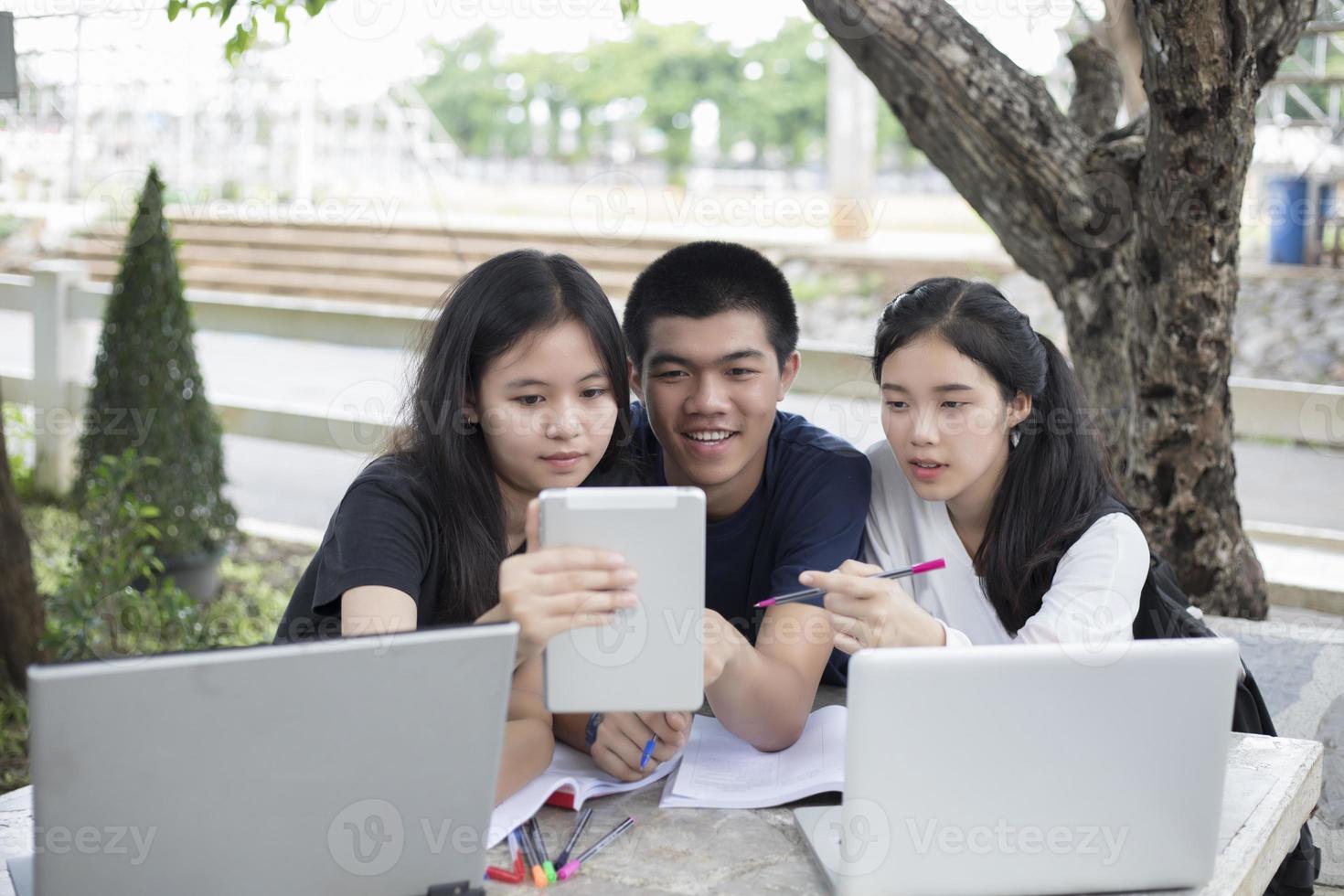 tre asiatiska studenter som använder en surfplatta för att studera foto