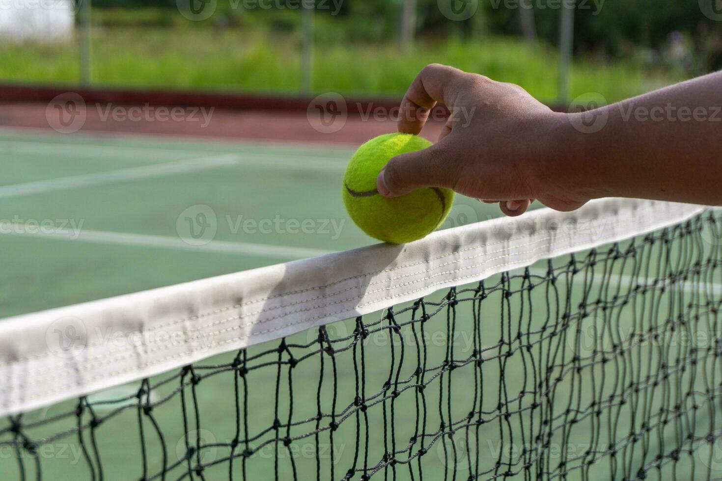 tennis spelare innehav tennis boll. hand sätta tennis boll på de topp av de netto. foto