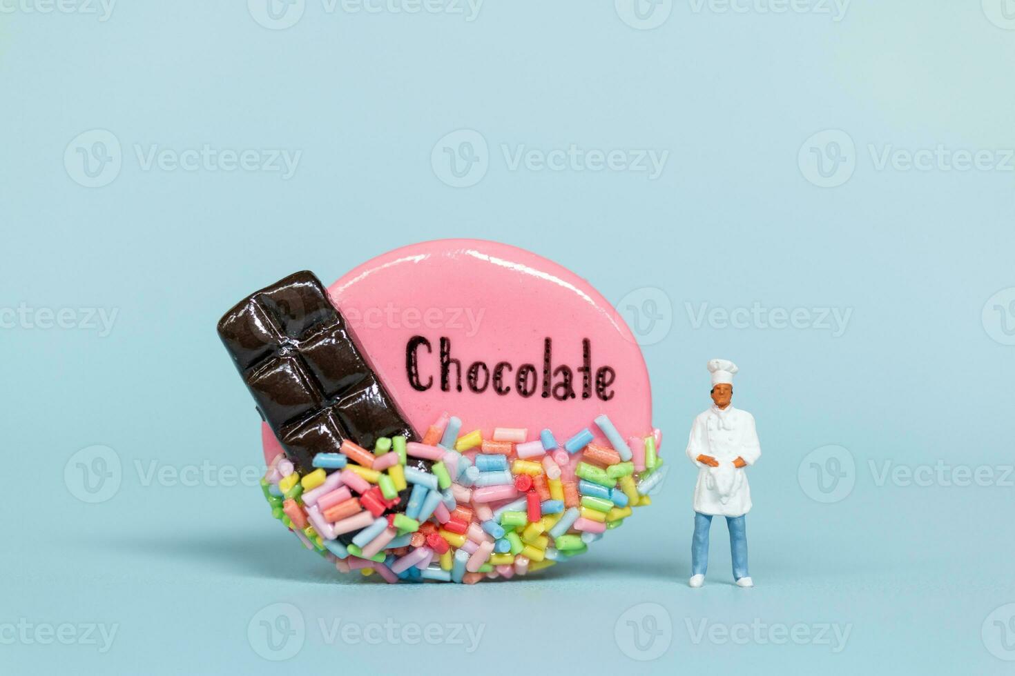 miniatyr- människor, kock med choklad kaka på en blå bakgrund. värld choklad dag begrepp foto