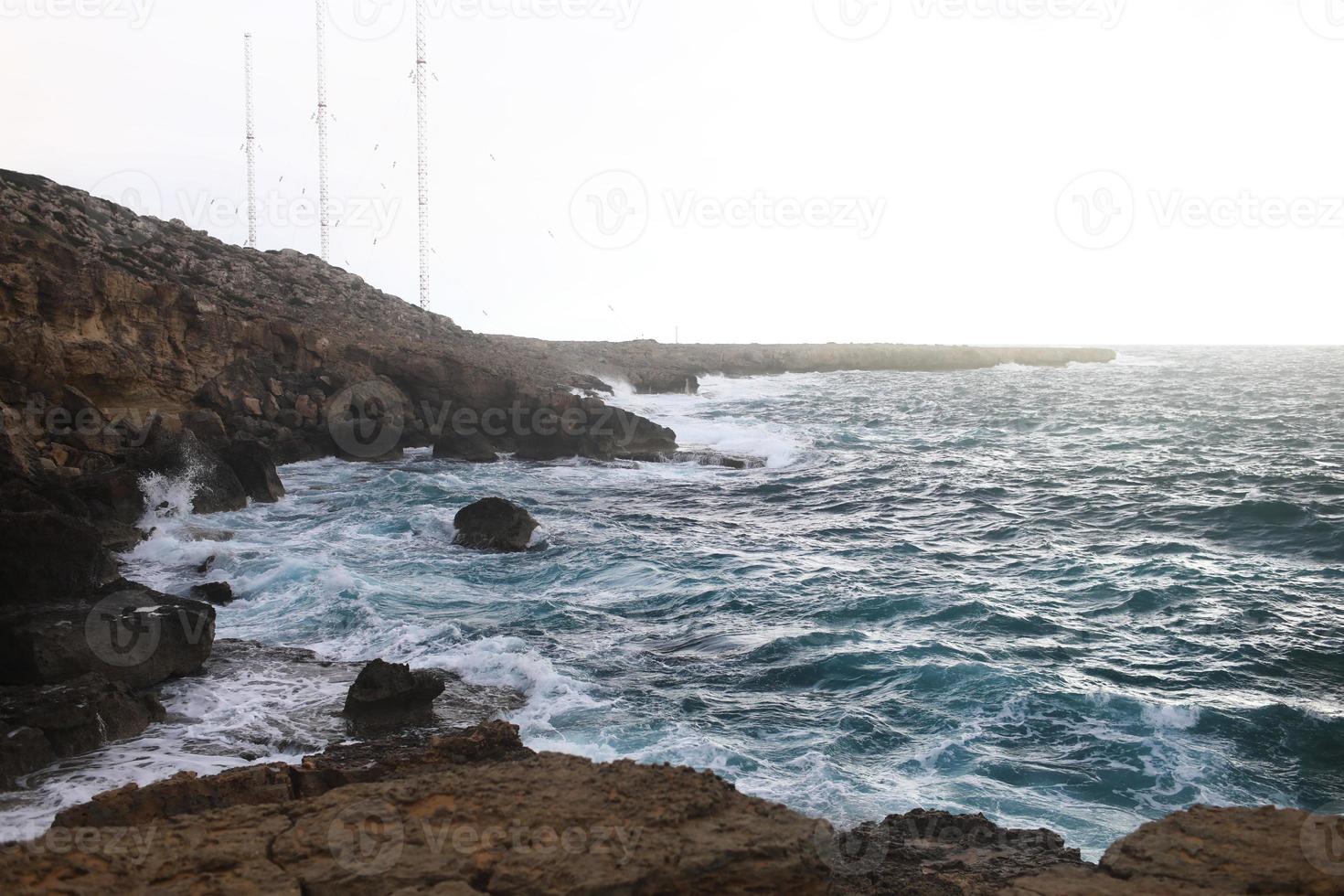 vågor som slår de klippiga klipporna på en strand i Cypern foto