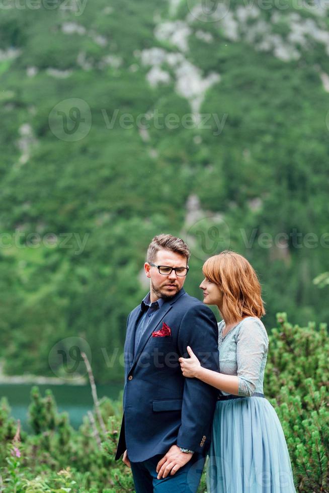 ungt par på en promenad nära sjön omgiven av bergen foto