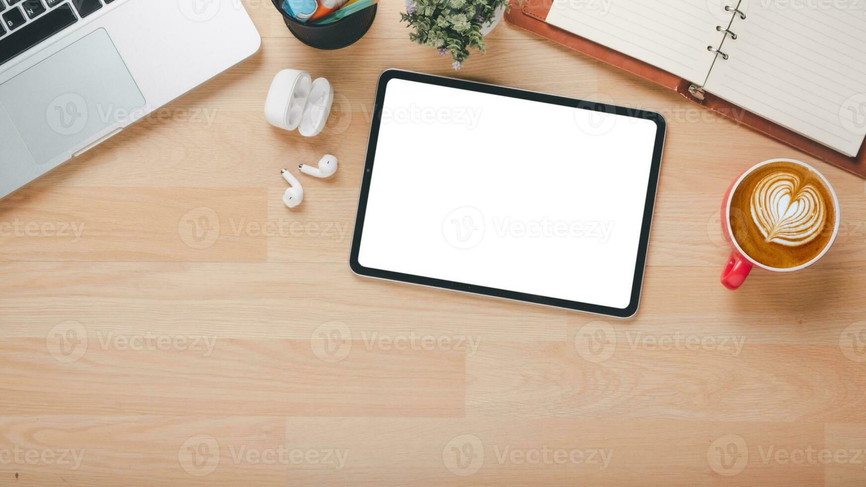 trä- skrivbord arbetsplats med tom skärm läsplatta, bärbar dator, hörlur och kopp av kaffe, topp se platt lägga med kopia Plats. foto