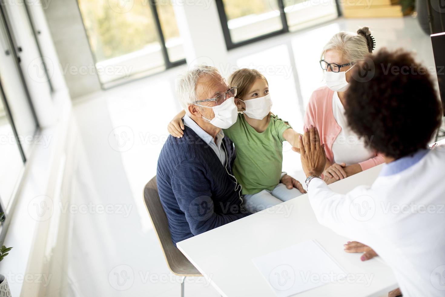 farföräldrar och barnbarn som pratar med en läkare foto