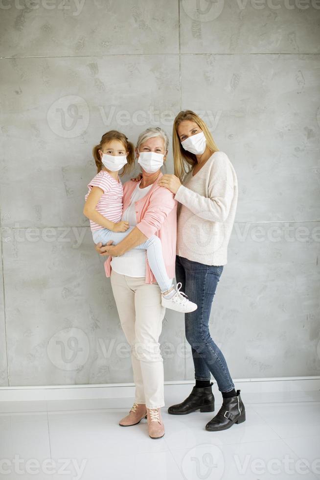 vertikal sikt av en mormor, mamma och barn som bär masker foto