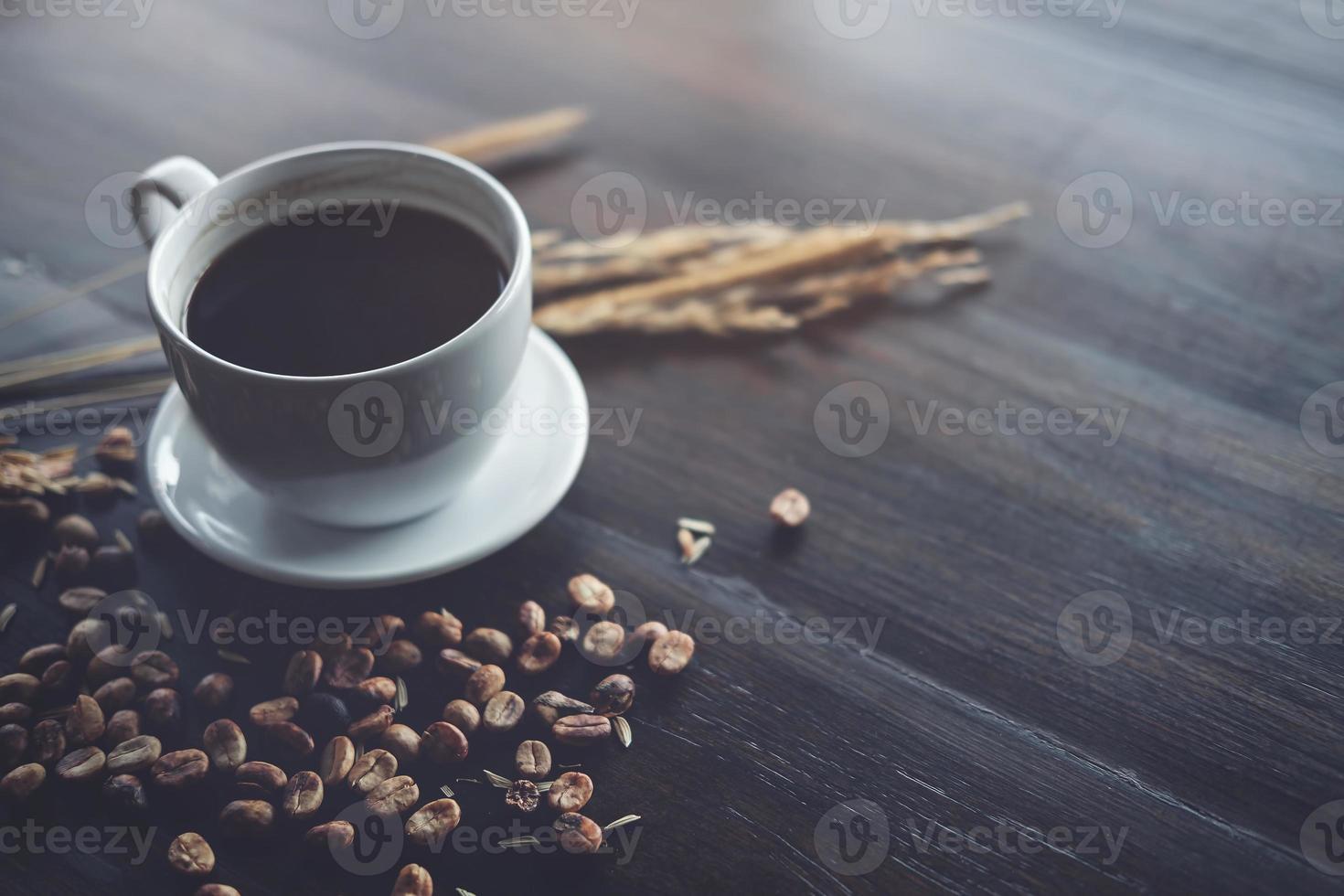 kaffeböna och svart kaffekopp på det wood skrivbordet på kaféet - tappningeffekt. foto