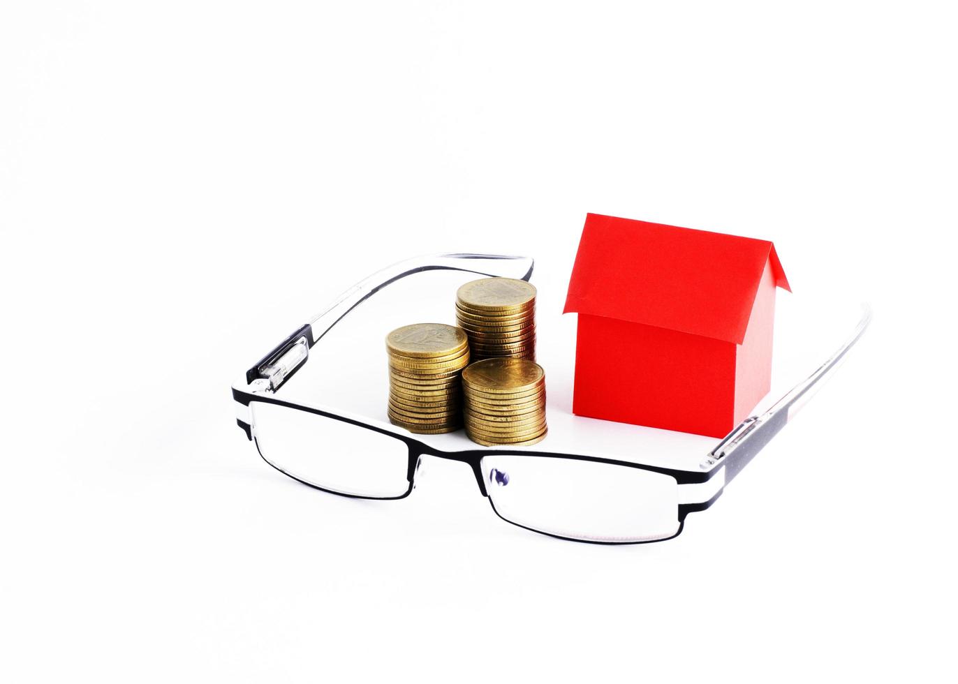 glasögon och pengar mynt stack och röda hus papper för lån pengar koncept foto