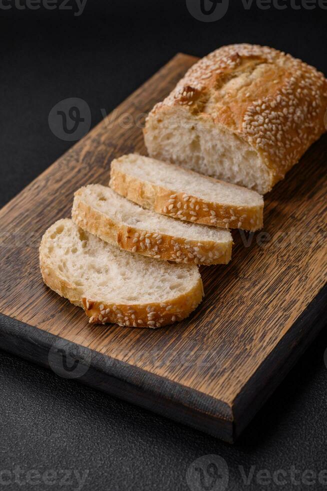 Krispig vete mjöl baguette med sesam frön på en trä- skärande styrelse foto