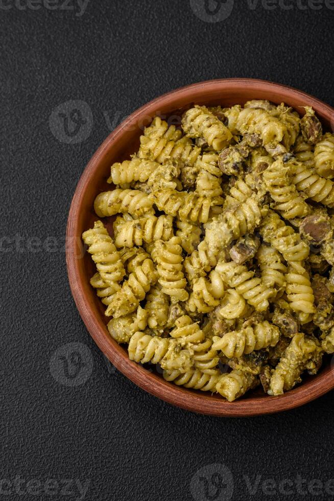 utsökt fusilli pasta med grön pesto sås, med salt och kryddor foto